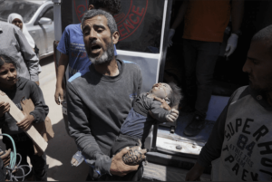 A Palestinian holds the body of a dead baby pulled from the rubble of a building destroyed in an Israeli airstrike in Nuseirat, Gaza Strip, Tuesday, May 14. – Photo by AP
